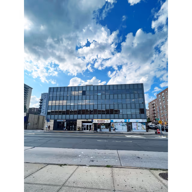 Glass-front commercial building with storefronts along a city street.