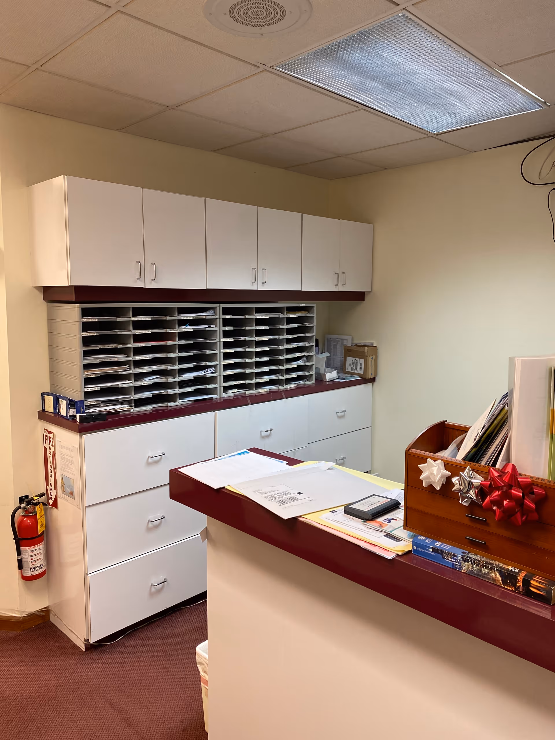 Reception area featuring a desk, wall of mail slots, and white storage cabinets.