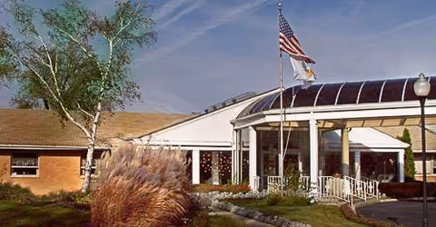 Front exterior of Alden Long Grove Rehab & Healthcare Center with American flag at entrance.