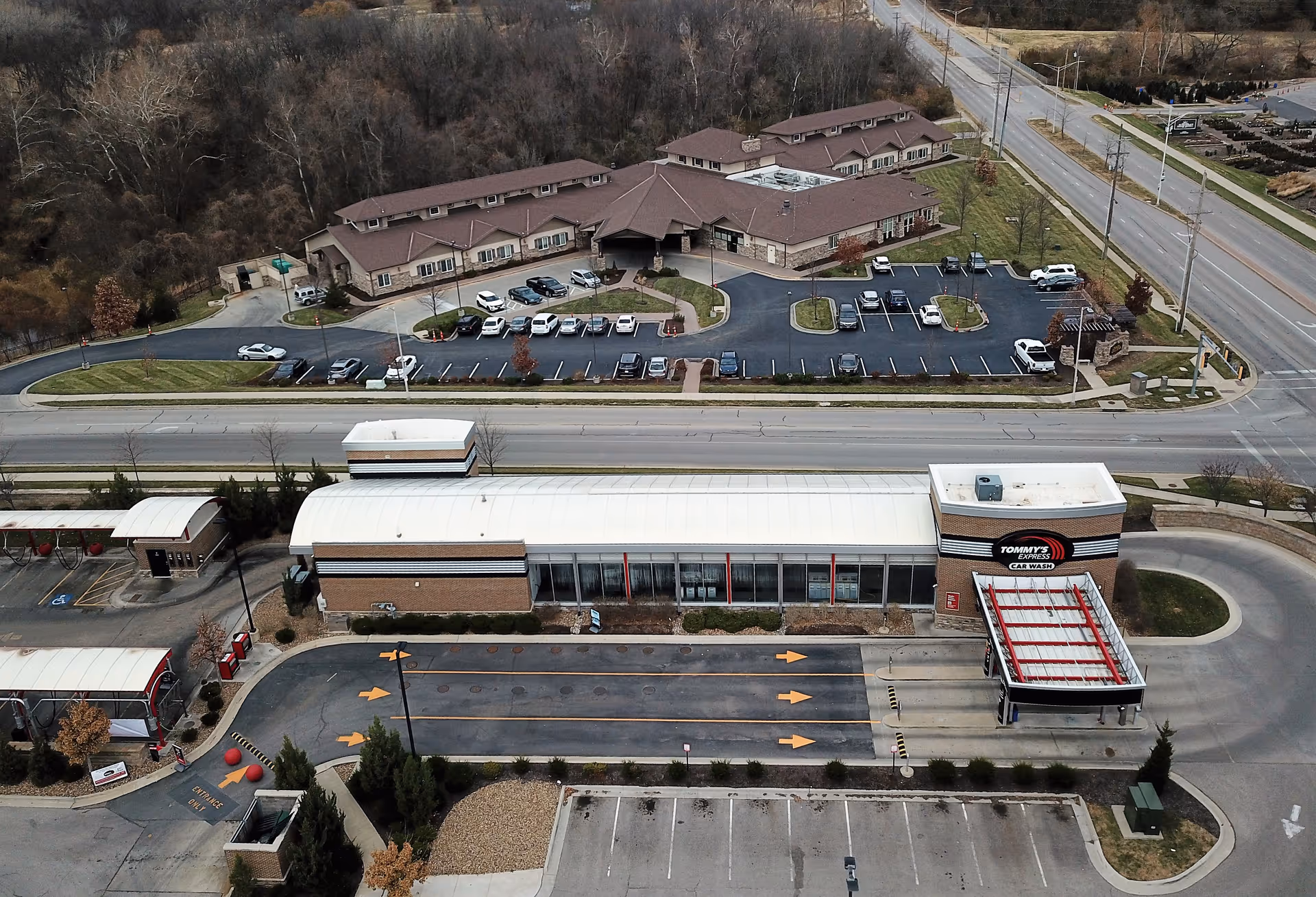 Aerial view of a car wash with adjacent shopping center and parking.