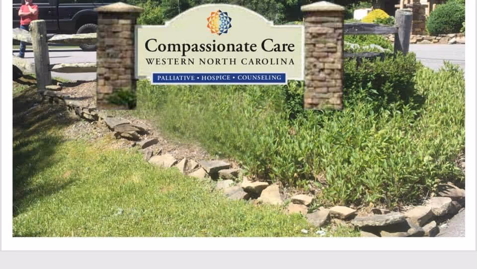 Entrance sign for Compassionate Care Western North Carolina with stone pillars and greenery