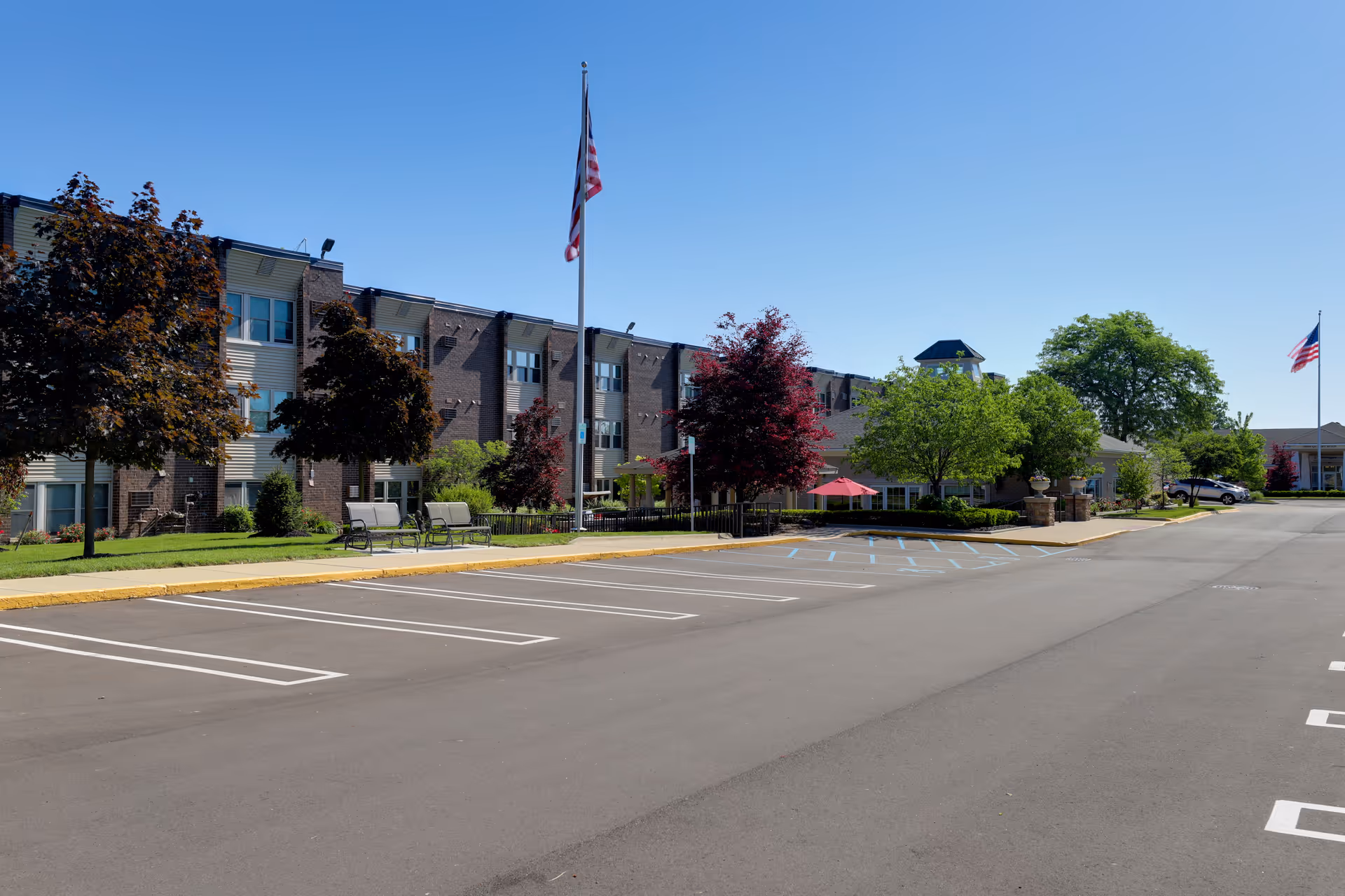 Exterior view of The Bellaire Senior Living building with manicured landscaping and parked cars.