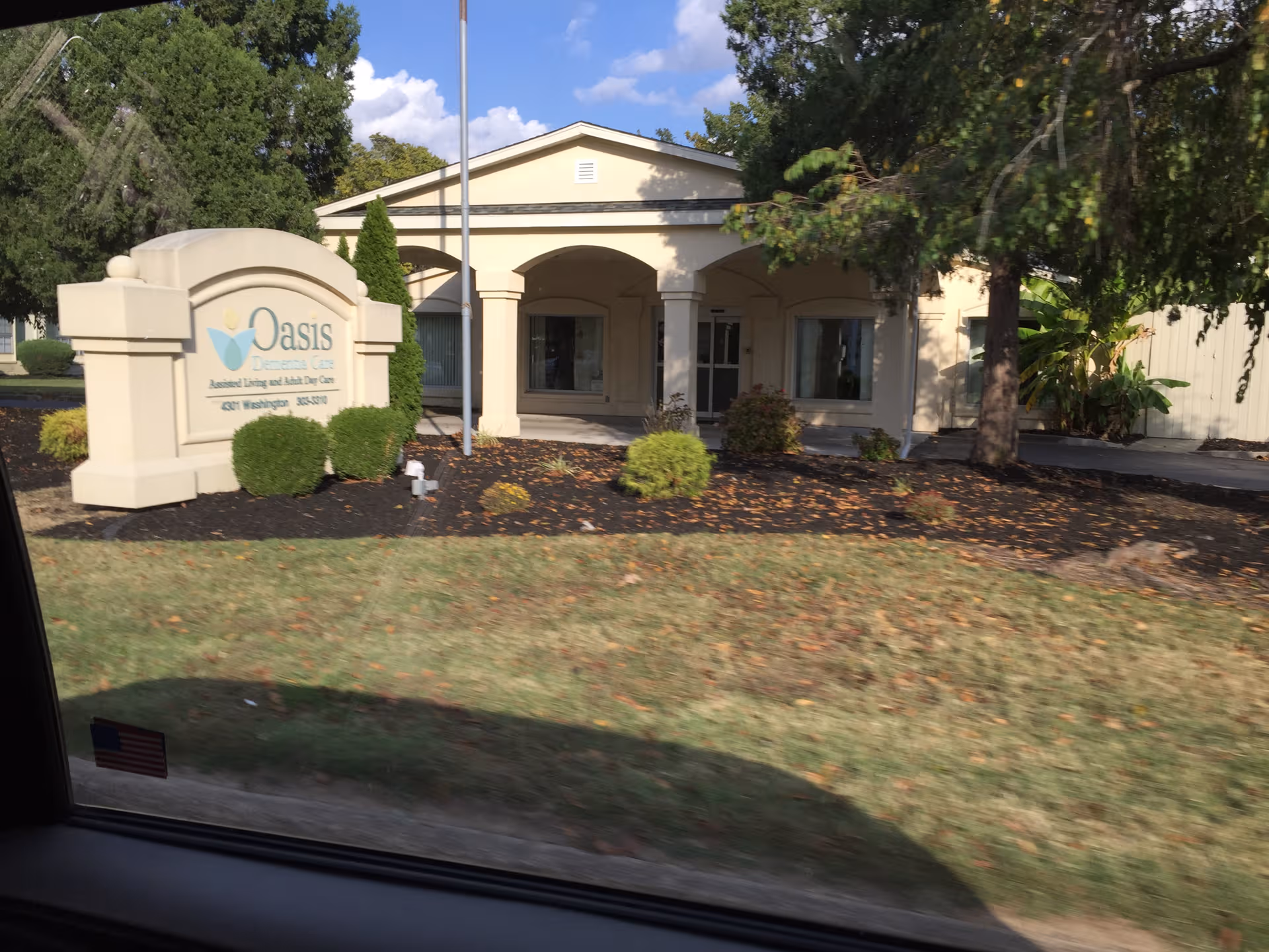 Exterior view of Oasis Dementia Care facility with entrance arches and landscaped front sign.