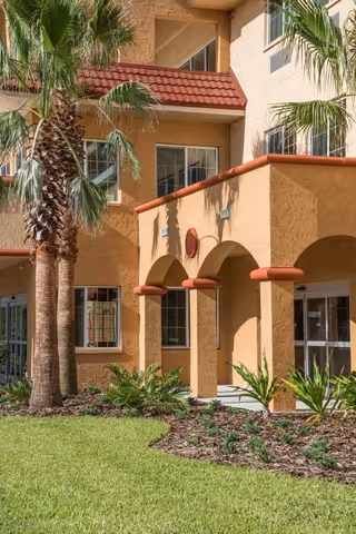 Exterior view of Seasons Largo facility entrance with arches, palm trees, and landscaping.