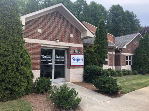 Senior Helpers facility exterior with glass doors and landscaped shrubs
