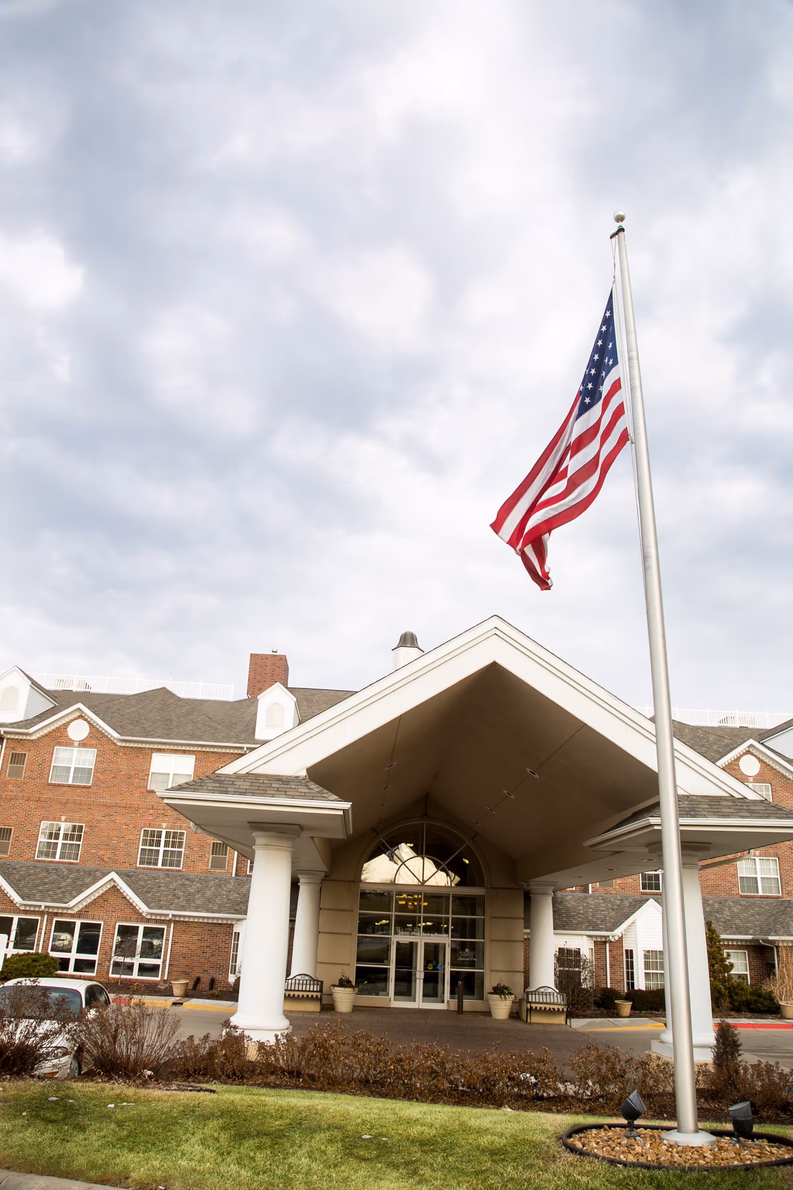 Exterior view of Savannah Pines Retirement Community with covered entrance and flag.