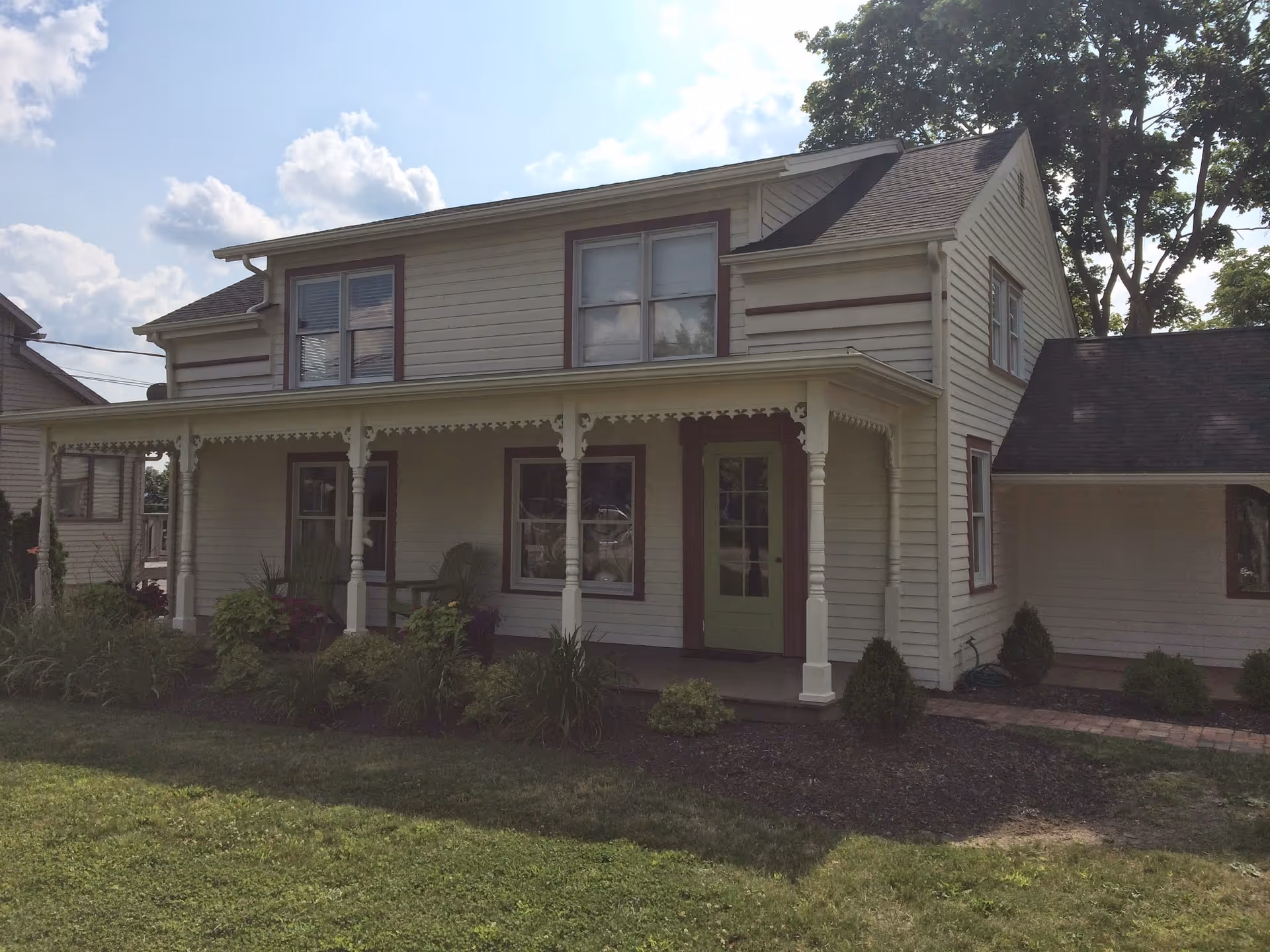 A white, two-story house-style senior facility with a covered front porch.