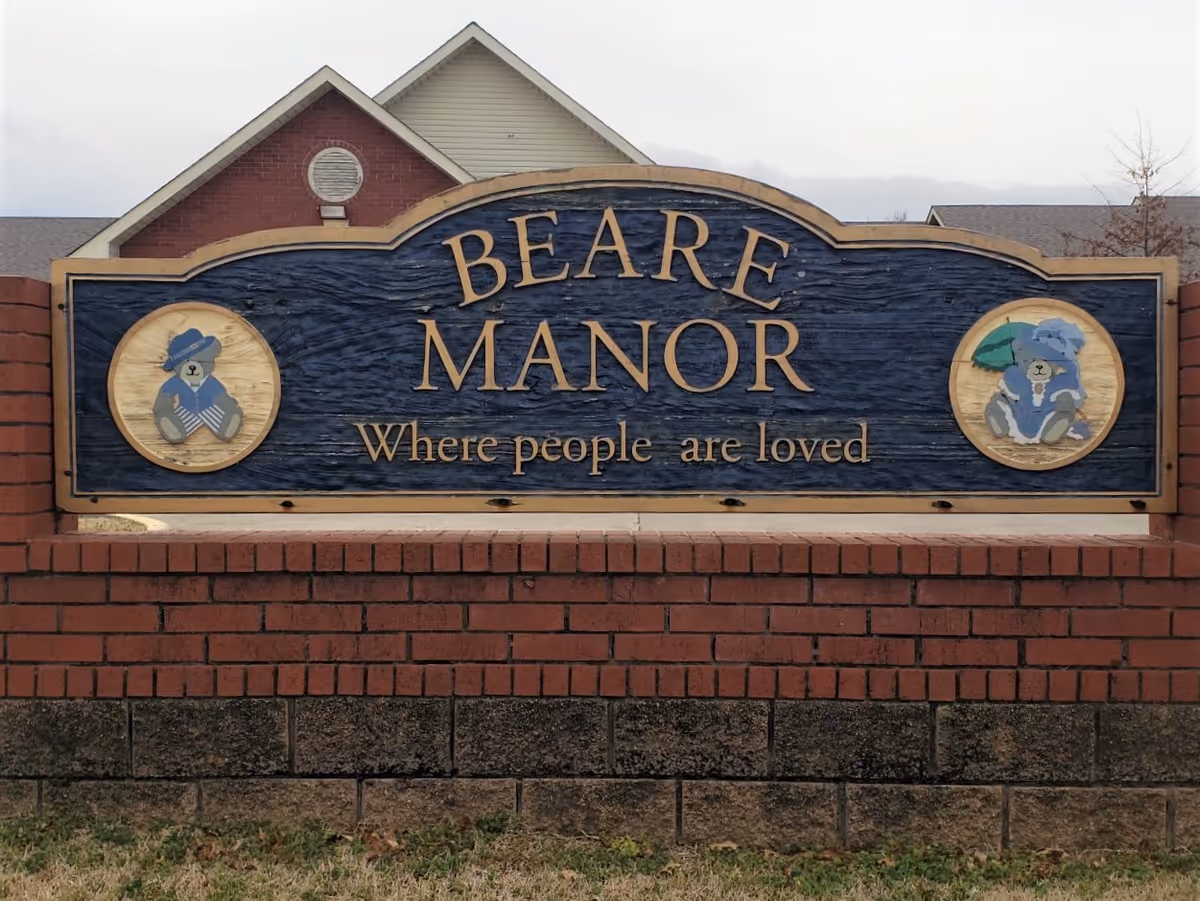 Large outdoor sign reading BEARE MANOR with the slogan 'Where people are loved'.