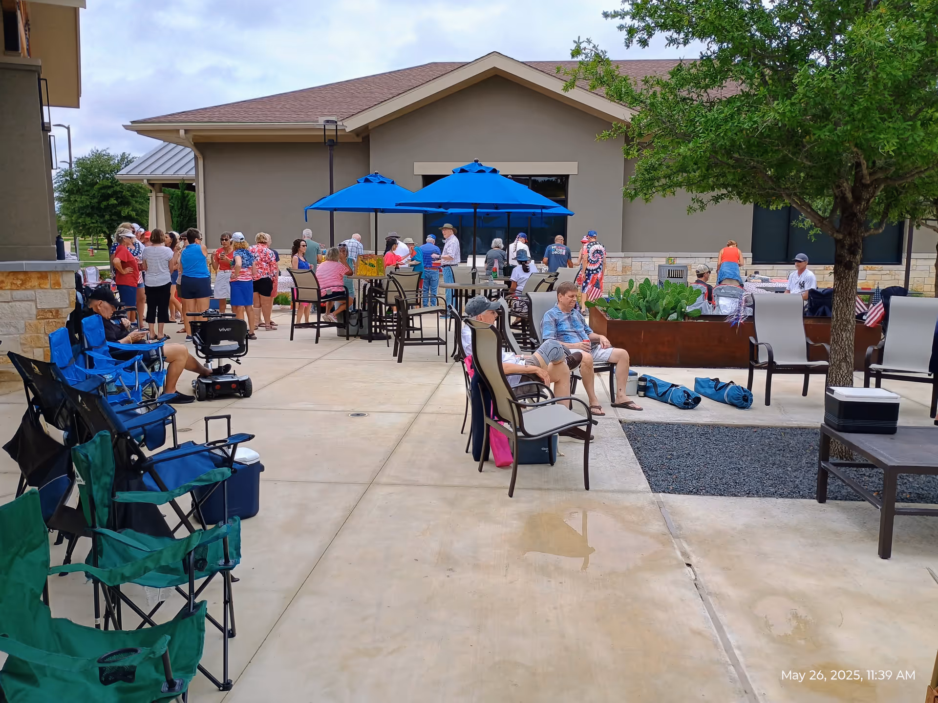 Outdoor patio at Sun City Texas with residents socializing under blue umbrellas.