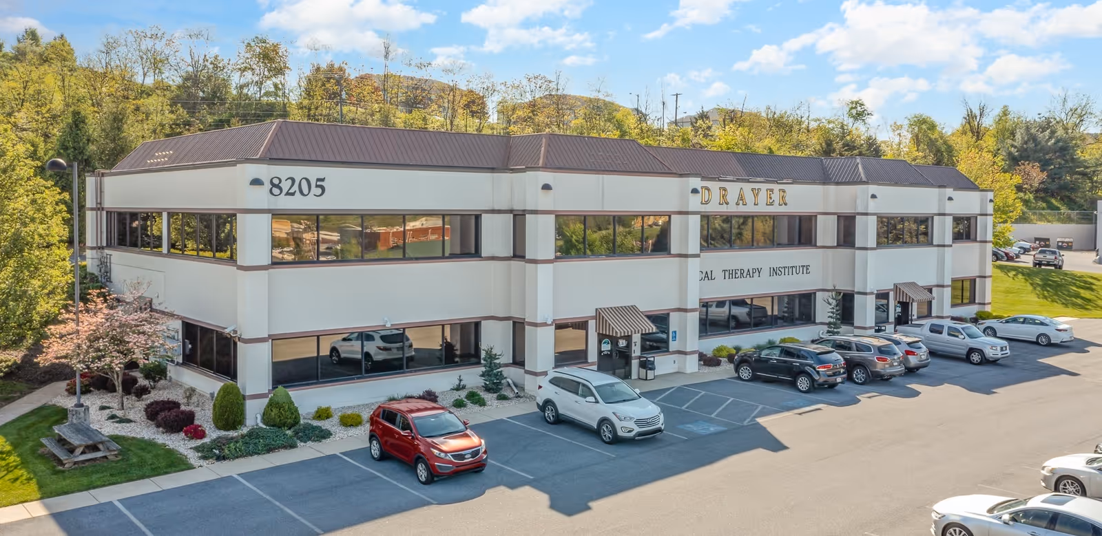 Exterior view of a two-story white building with Drayer sign and parked cars.