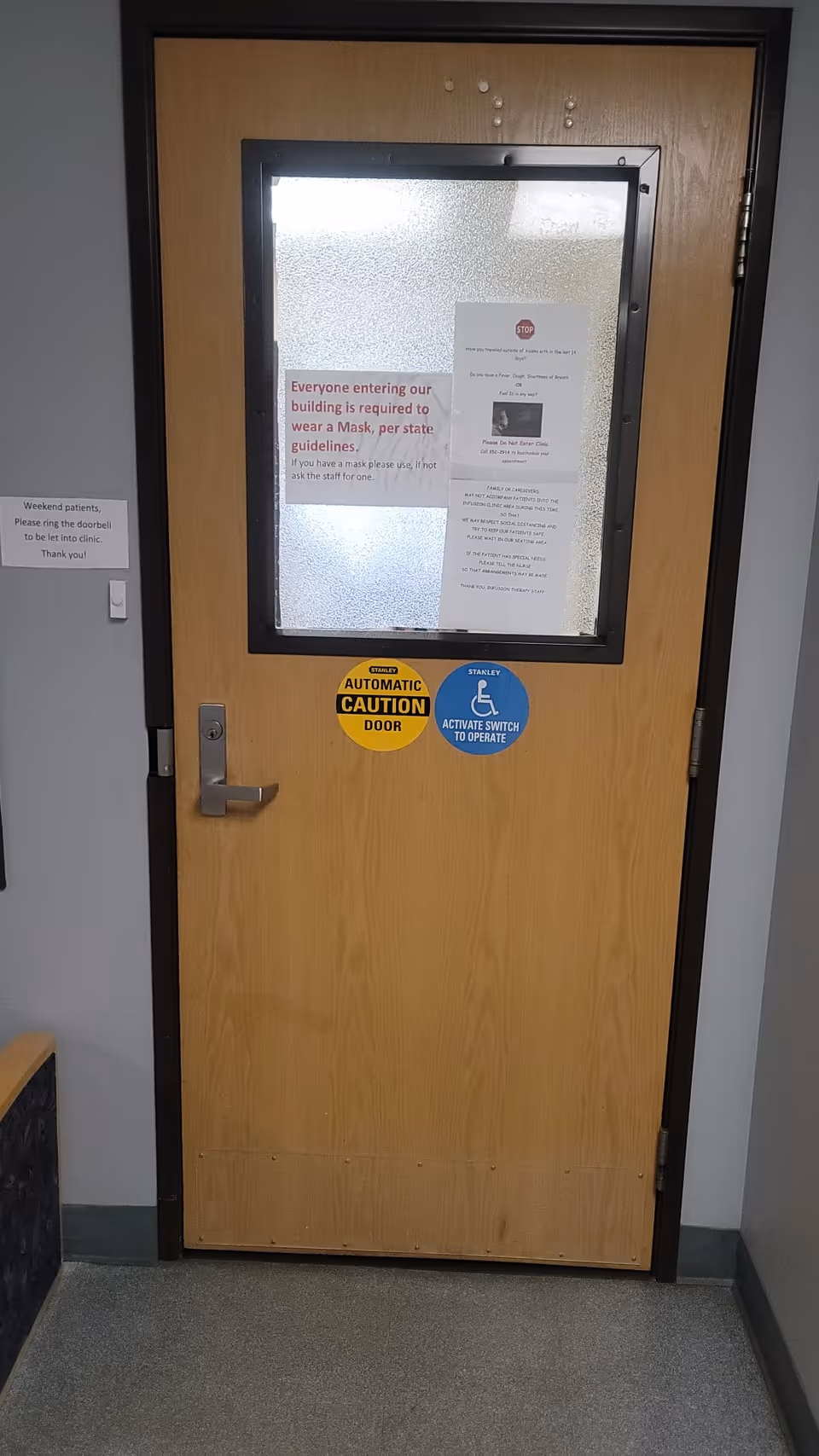 Wooden interior door with frosted window, hallway signage, and accessibility safety decals.