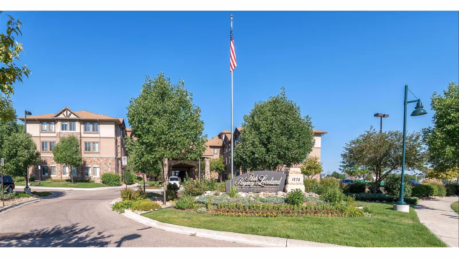 Exterior view of Bethesda Gardens senior living with manicured grounds and a flagpole.