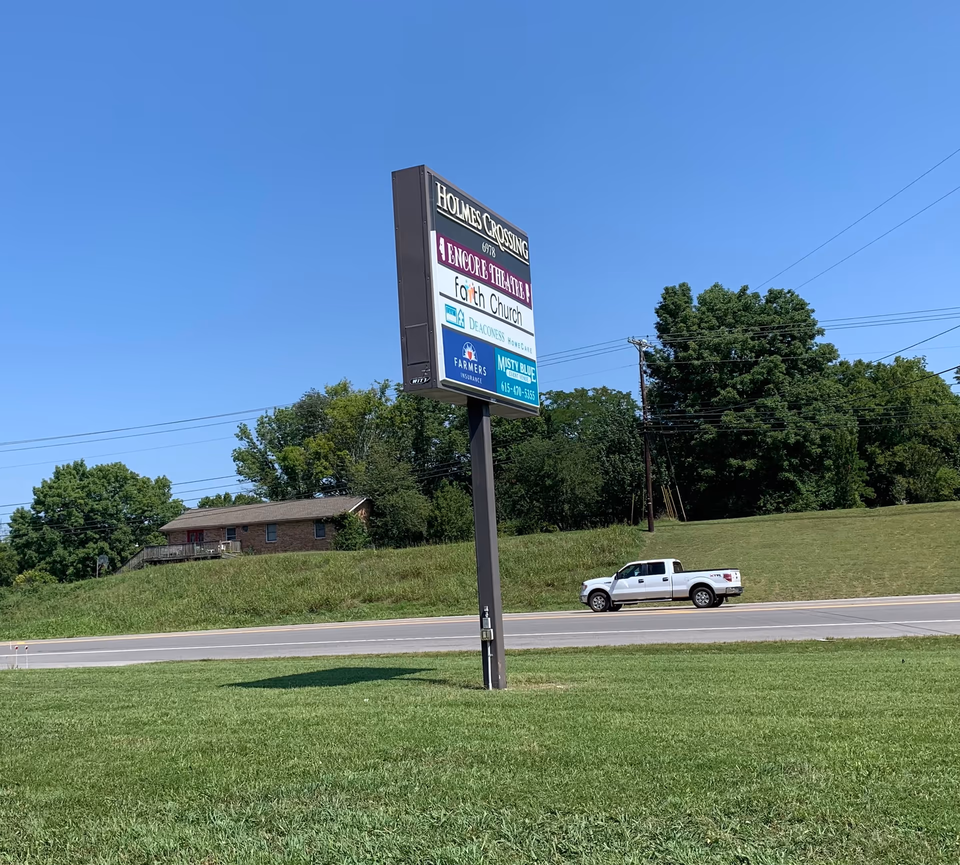 Tall roadside sign for Deaconess HomeCare beside a brick building and green lawn.