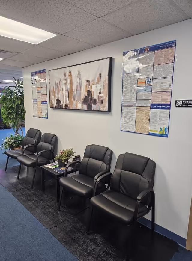 Row of black leather chairs along a wall in a waiting area with posters.