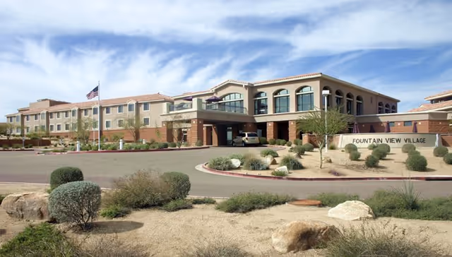 Front view of Fountain View Village senior living facility with landscaped grounds and driveway.