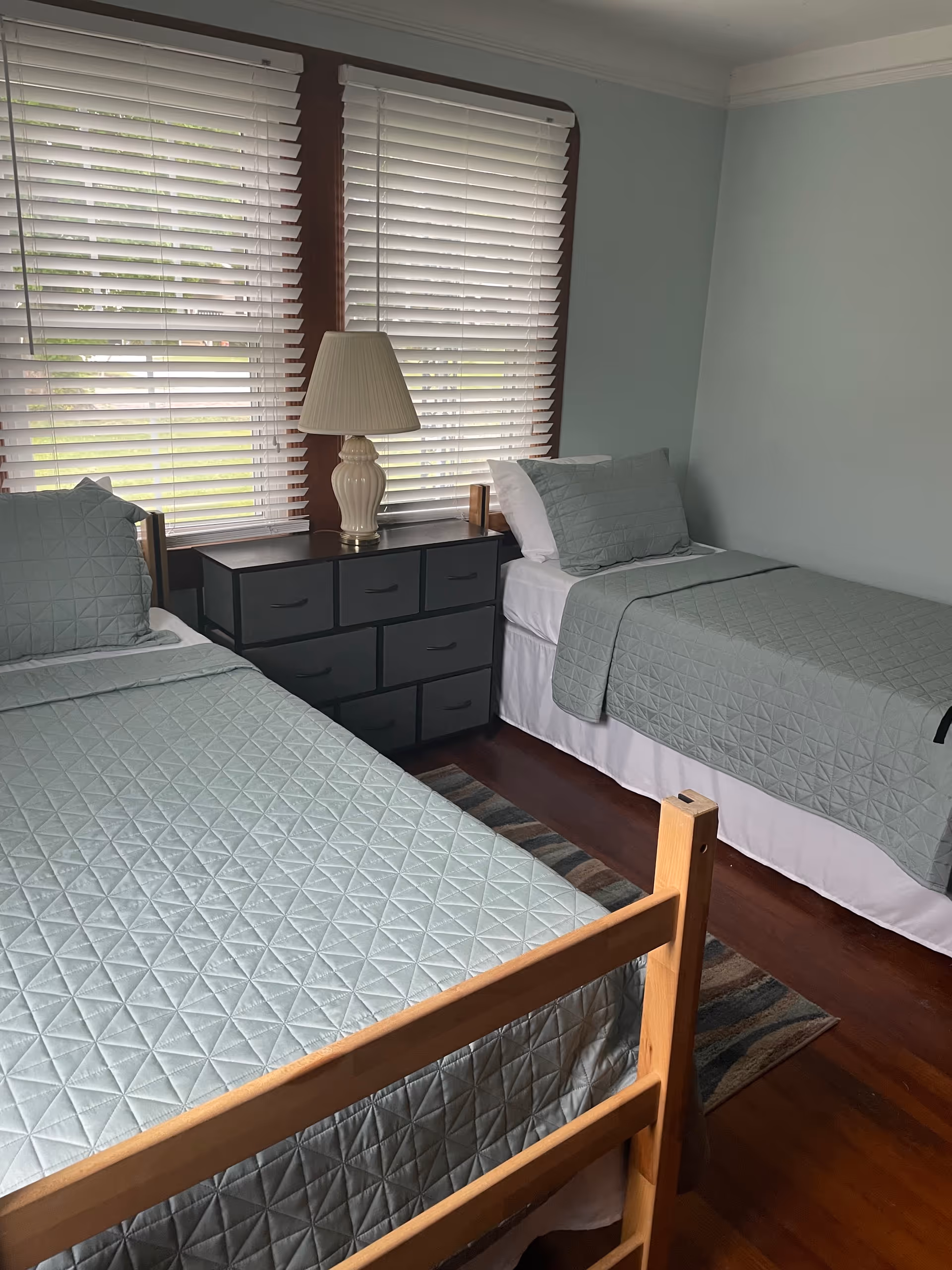 Two twin beds with matching quilts and a nightstand between them in a tidy bedroom.