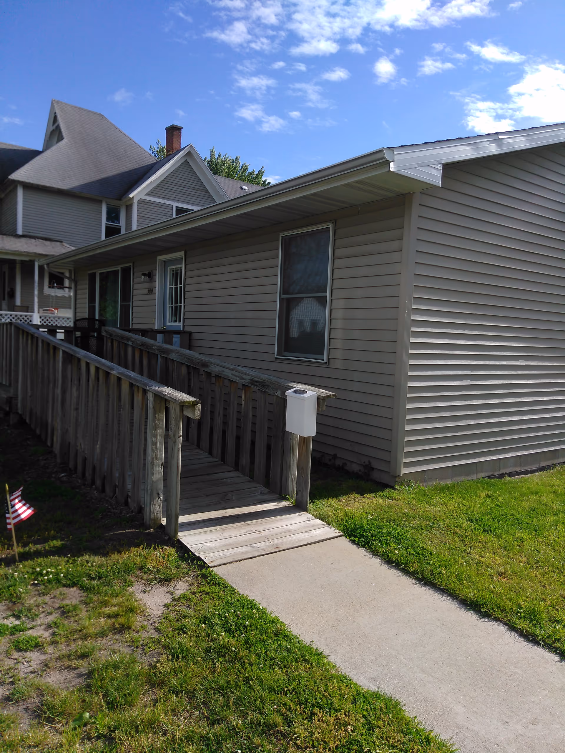 Exterior view of a senior living facility with a wooden ramp and walkway.