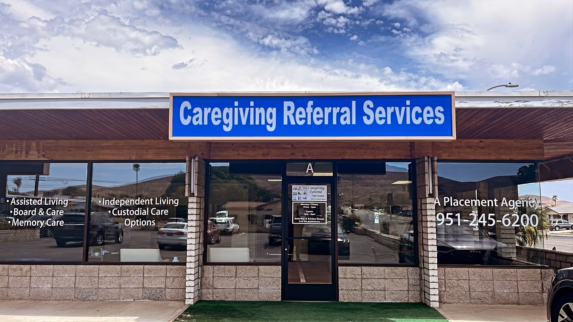 Blue sign 'Caregiving Referral Services' above the storefront entrance of a building.