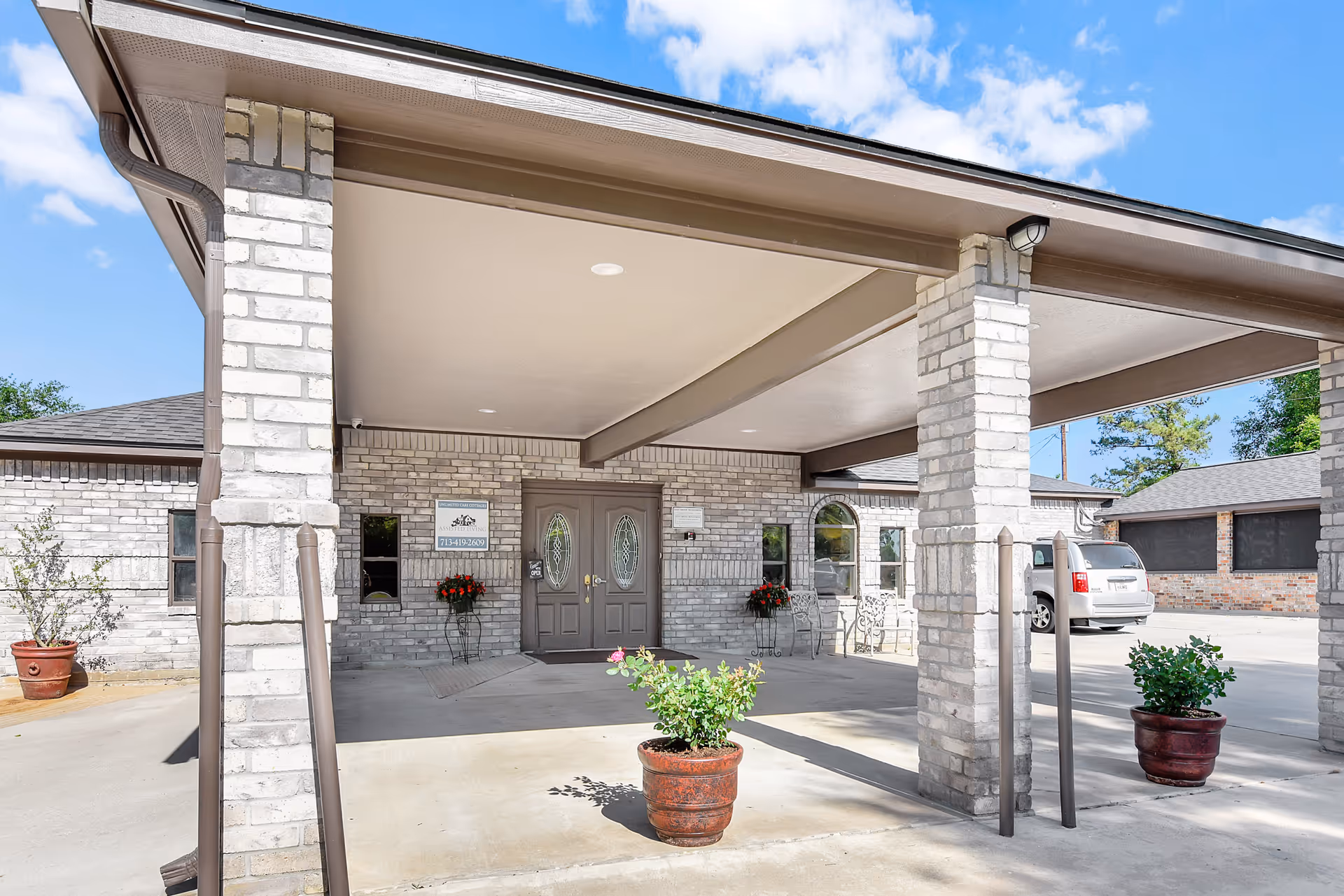 Exterior view of Willis House entrance with brick pillars, double doors, and potted plants.