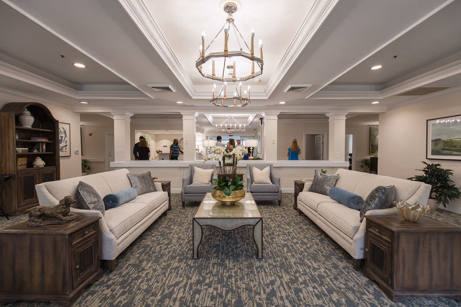 Spacious lounge at The Charlotte senior living, with beige sofas, coffee table, and back reception area.