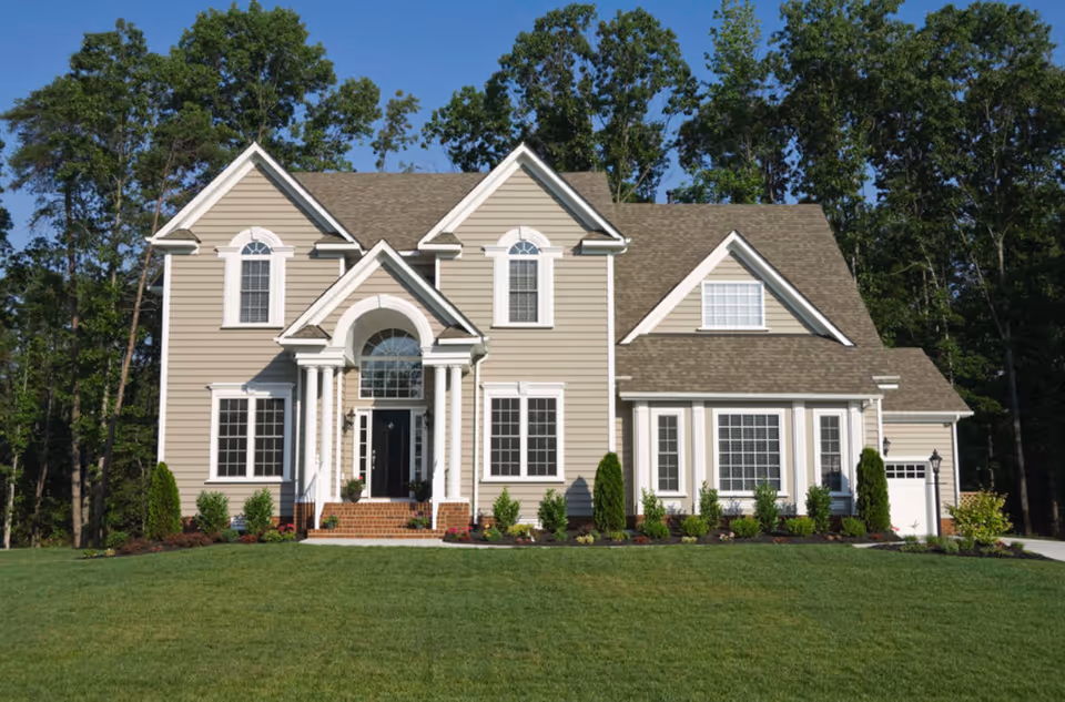Beige two-story building with a grand front entrance, columns, and a manicured lawn.