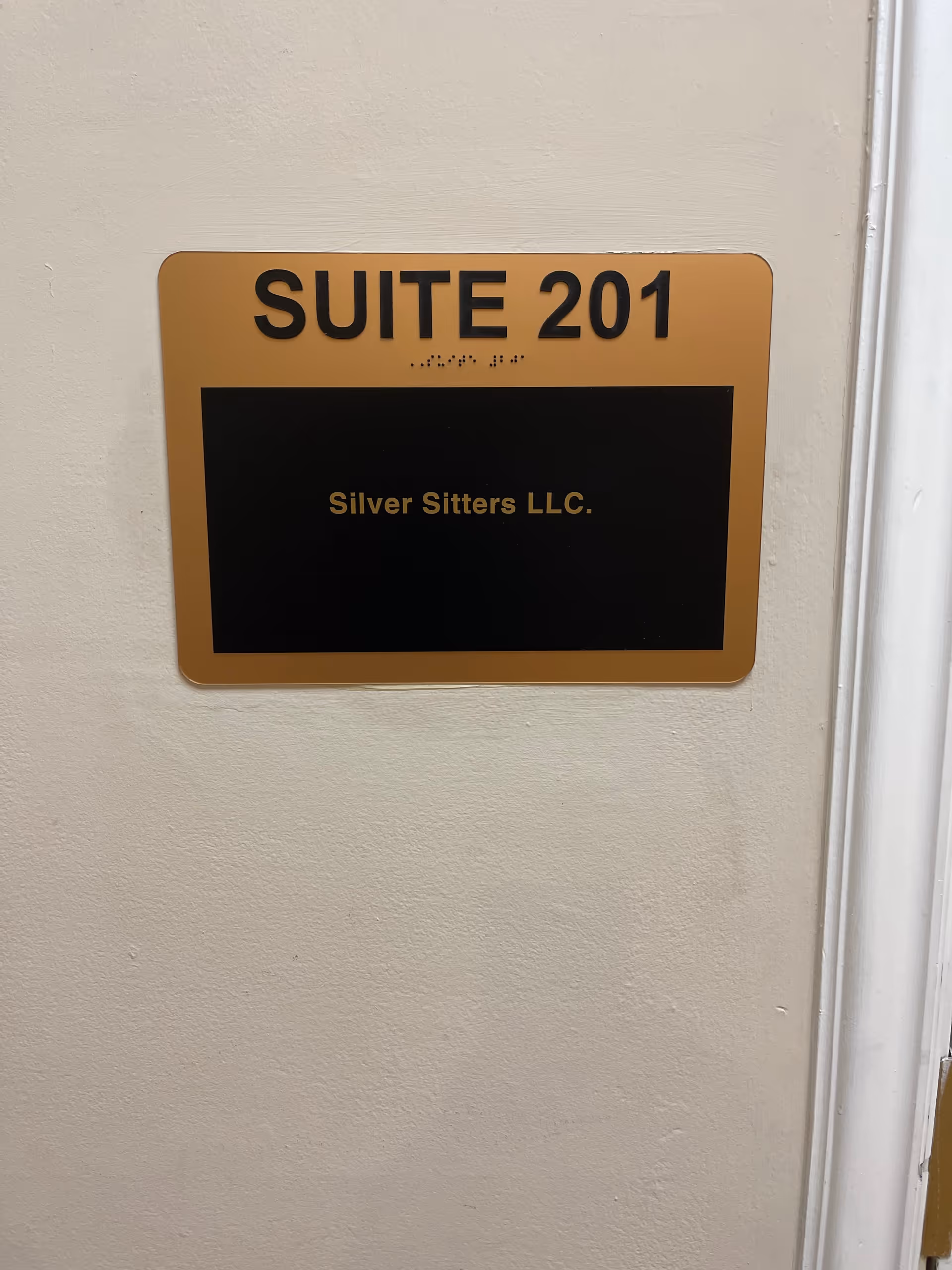 Wall plaque showing SUITE 201 and Silver Sitters LLC in a hallway.