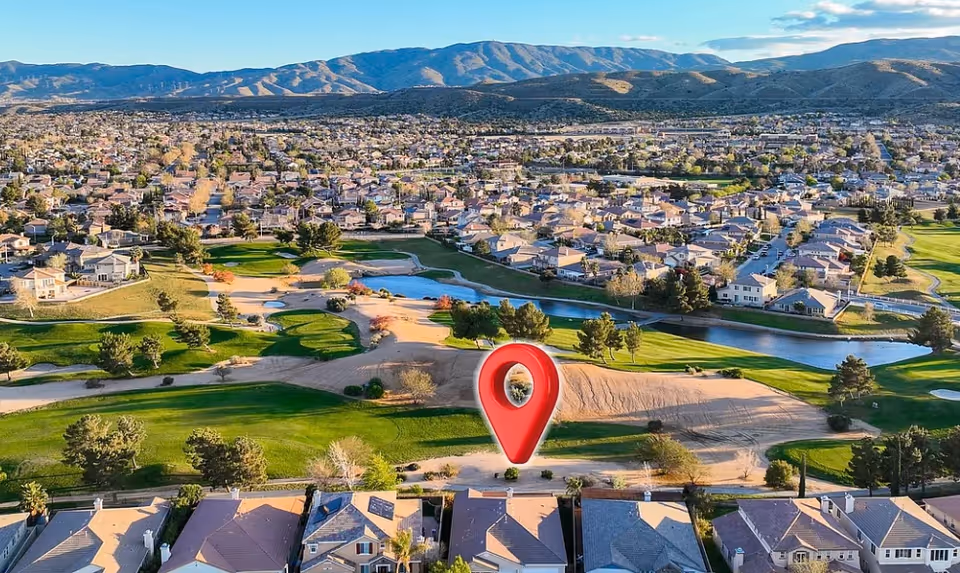 Aerial view of a suburban senior community with a golf course and a red pin marker.