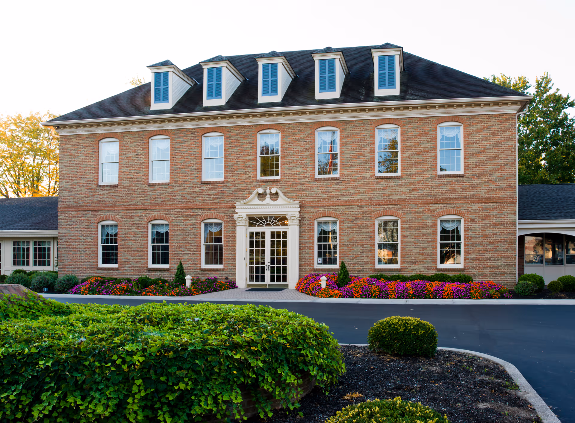 Brick senior living facility with a grand entrance and manicured landscaping.