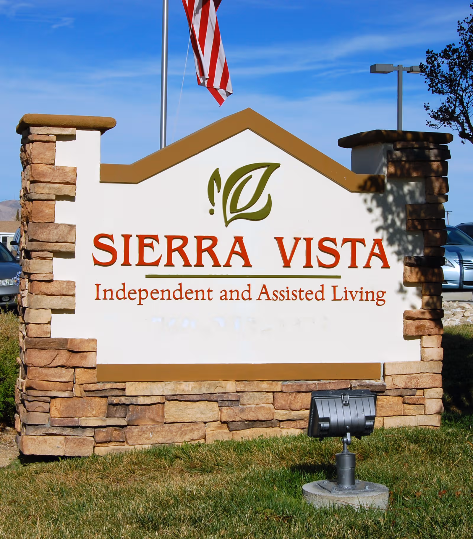 Stone-framed exterior sign reading Sierra Vista Independent and Assisted Living, set against a blue sky.