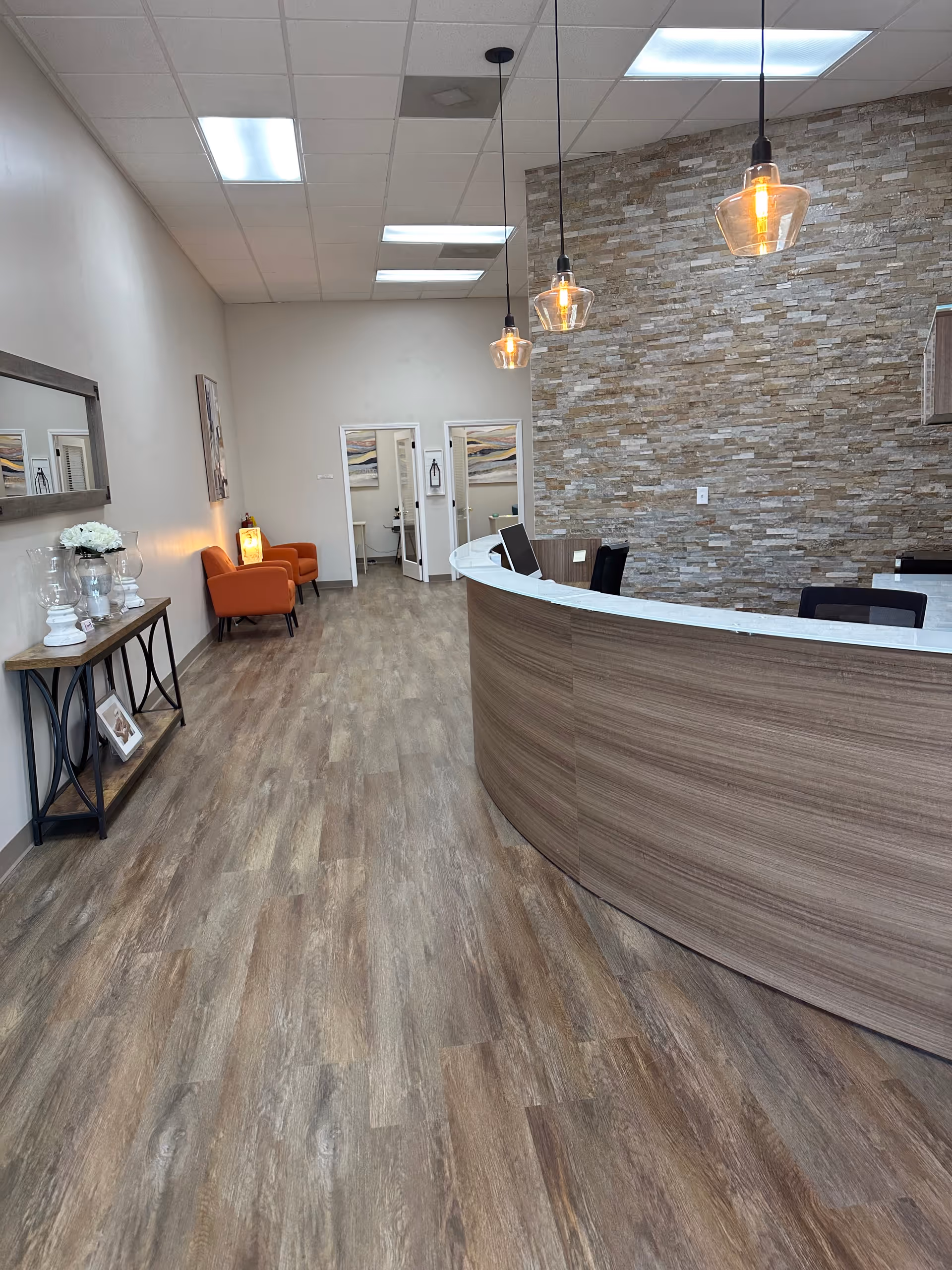 Curved reception desk in a modern, well-lit lobby with stone wall and seating.