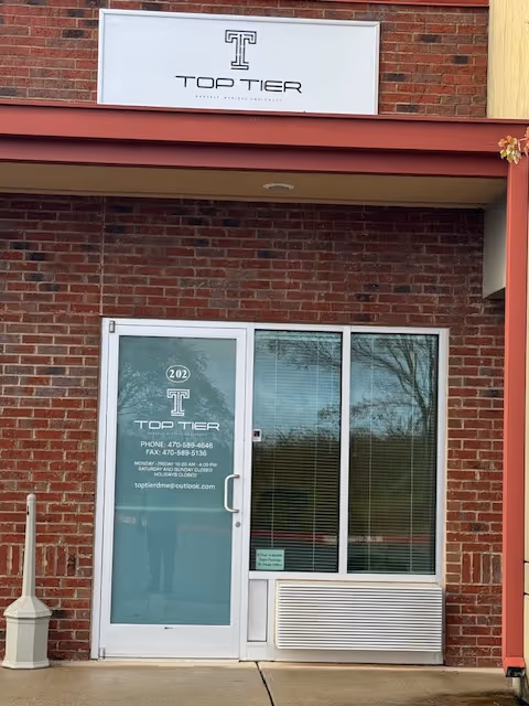 Brick building facade with Top Tier sign, glass entrance door and adjacent windows.