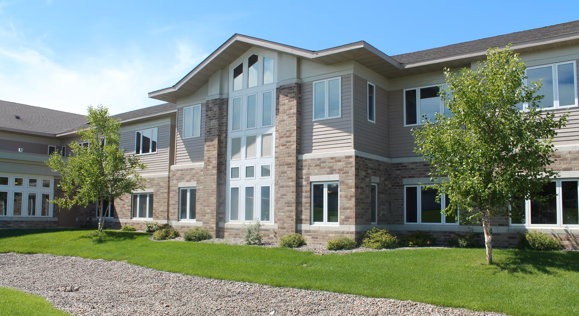 Country Manor Extended Service I building exterior with brick facade, large windows, and landscaped lawn.