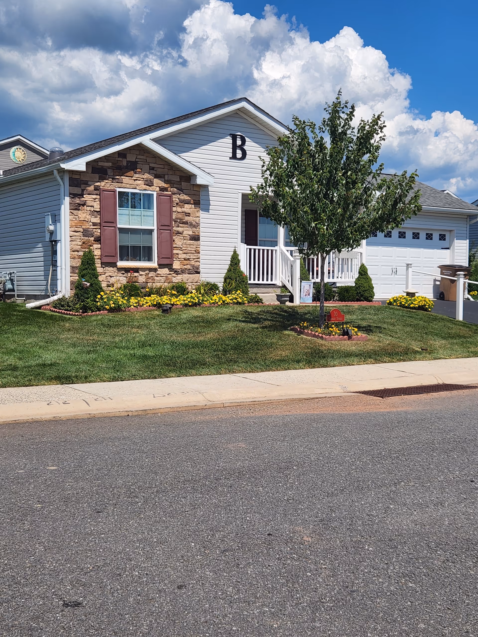 Front view of a single-story senior living building with landscaped lawn and tree