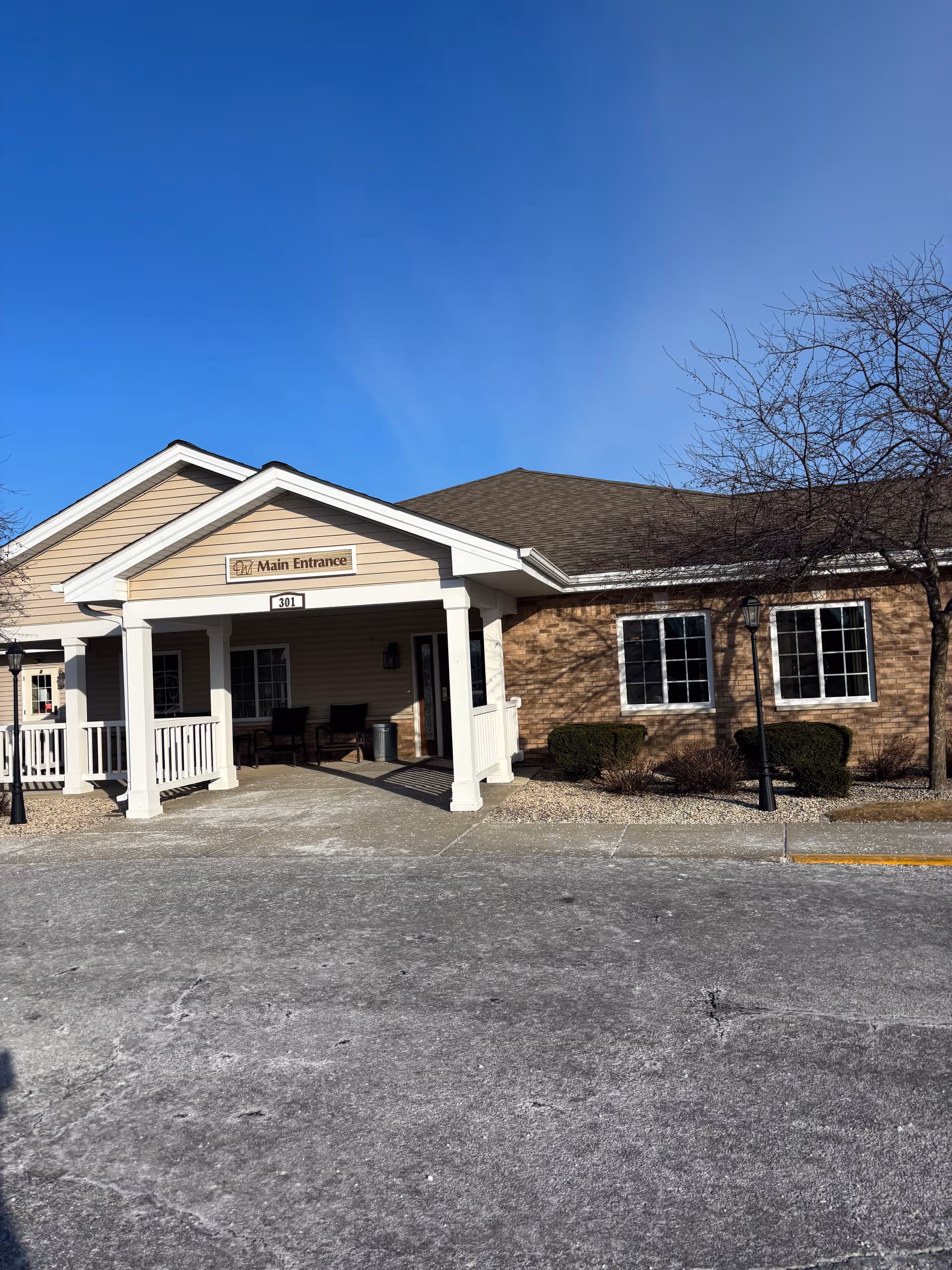 Senior living facility entrance with a covered porch, brick exterior, and main entrance sign.