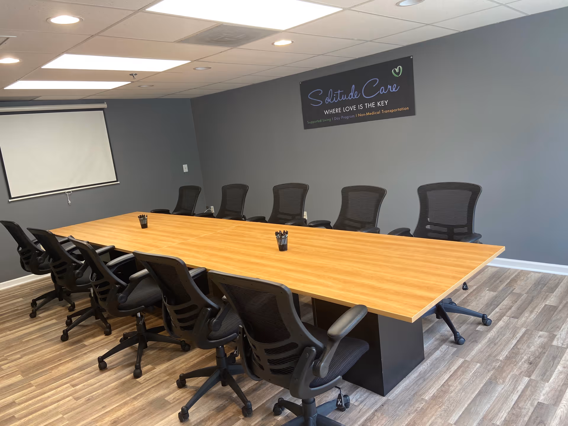A long conference table with multiple black chairs and a Solitude Care banner.