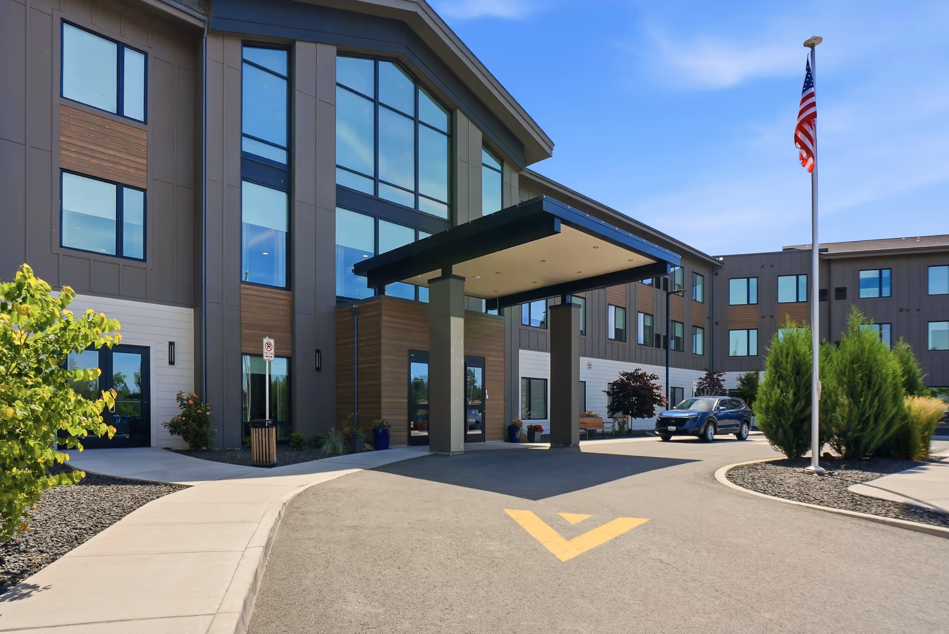 Modern senior living facility exterior featuring a covered entrance and parking lot.