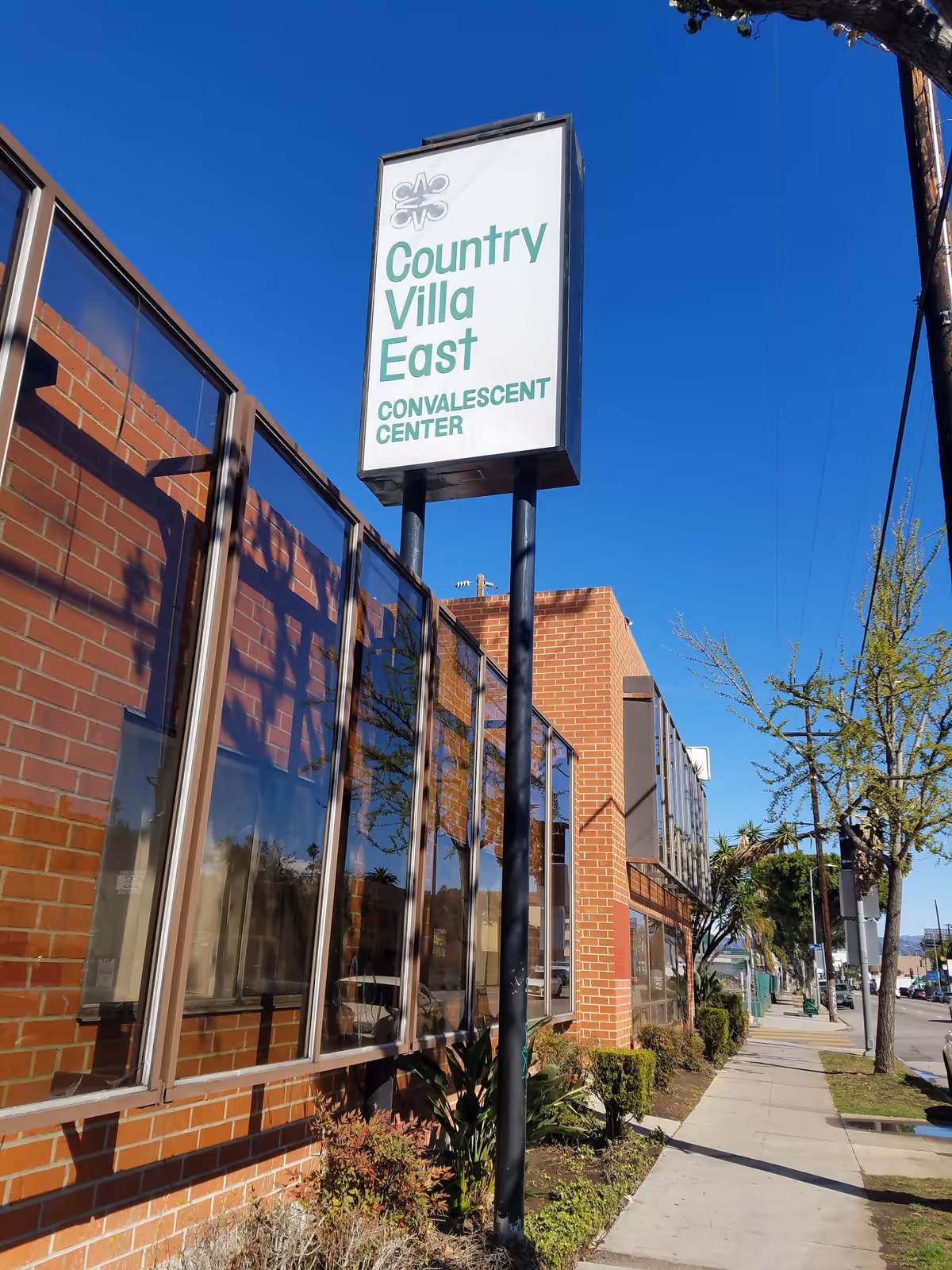 Exterior brick building with a tall sign reading Country Villa East Convalescent Center.