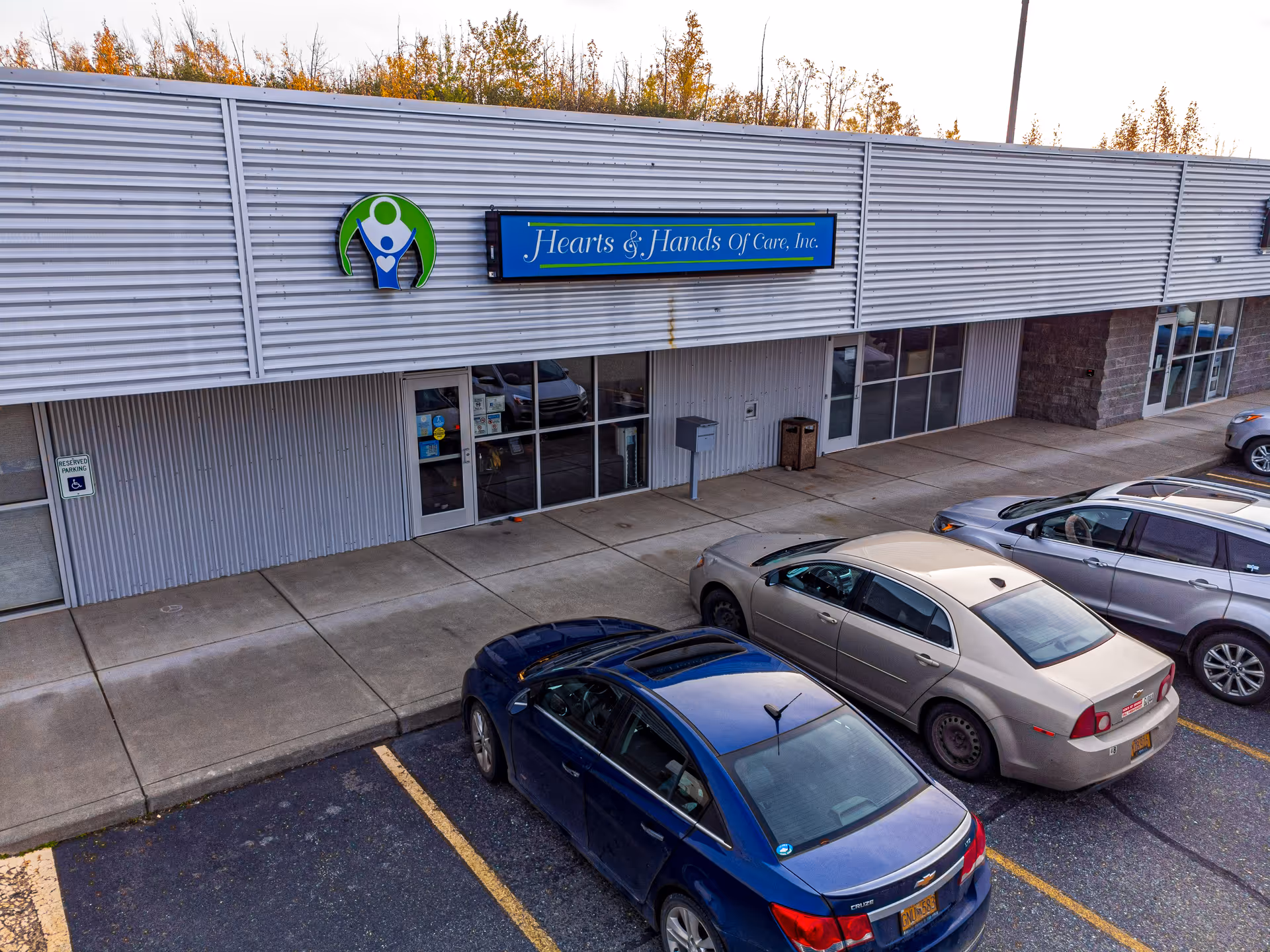 Exterior view of Hearts & Hands Of Care facility with cars parked in front.