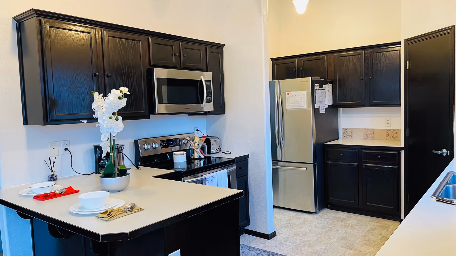 Compact kitchen with dark cabinets, stainless appliances, and a peninsula breakfast island.