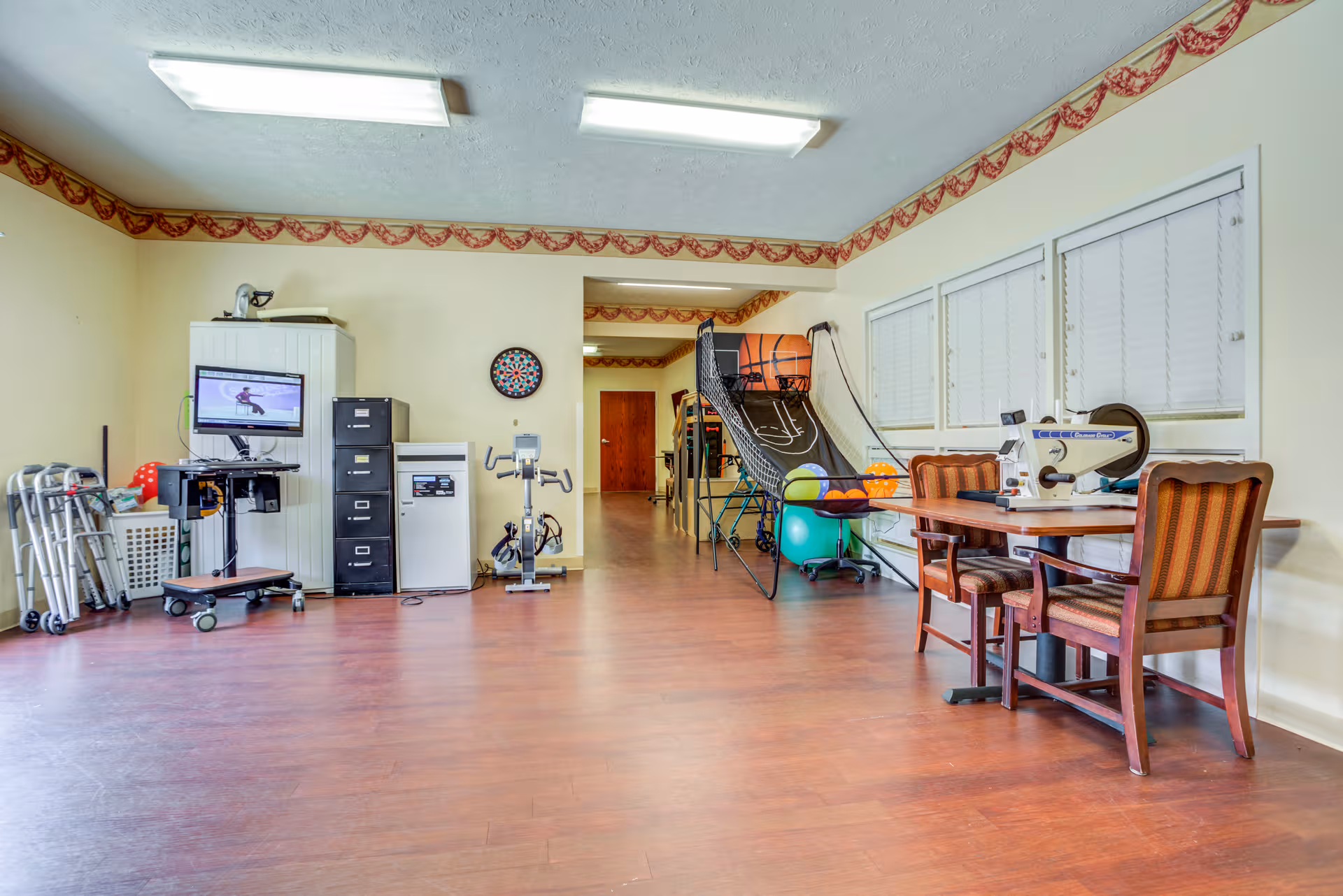 Spacious indoor activity room in a senior facility with exercise equipment and seating.