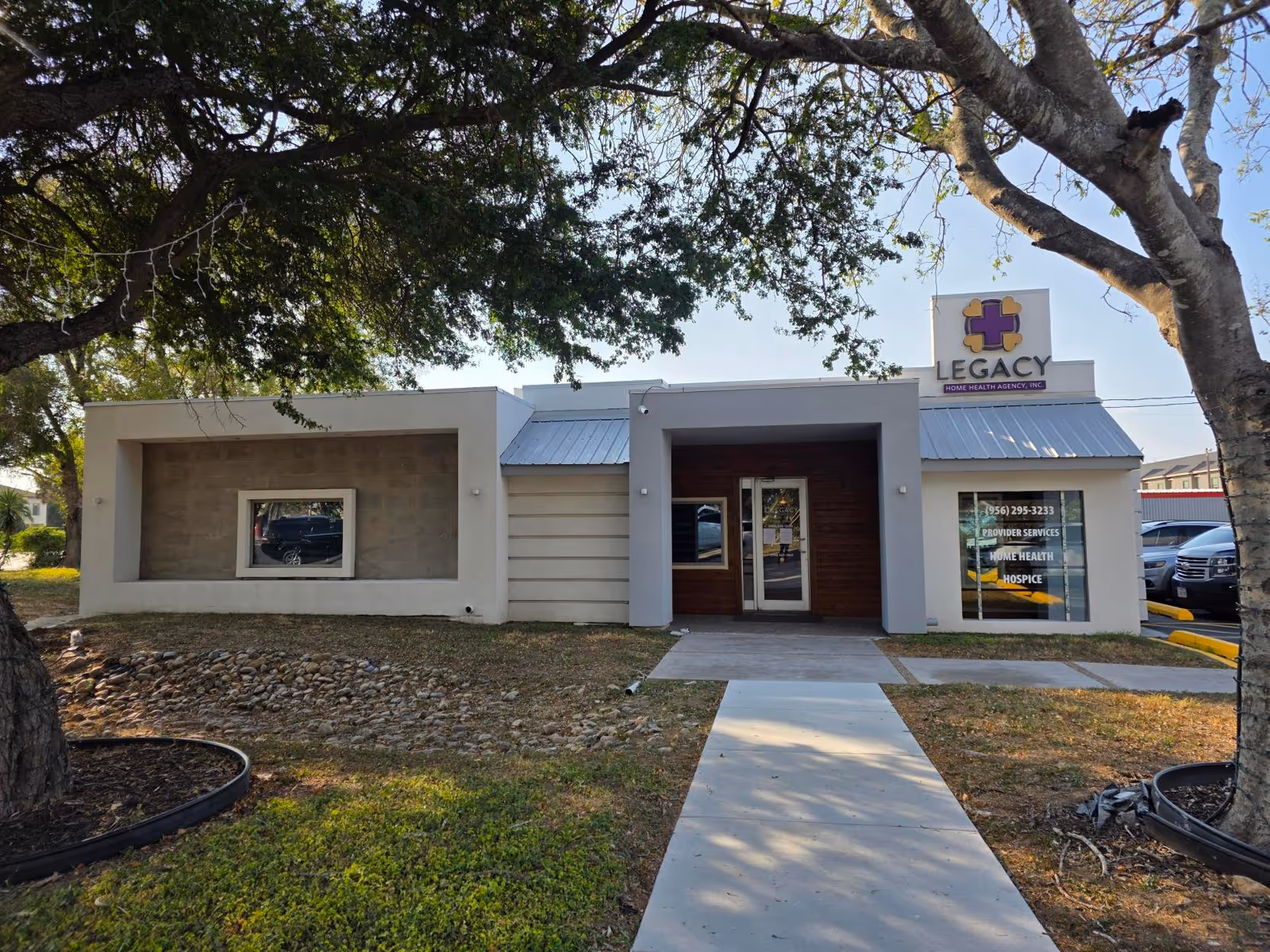 Modern single-story medical facility with glass doors and Legacy sign, walkway, and trees.