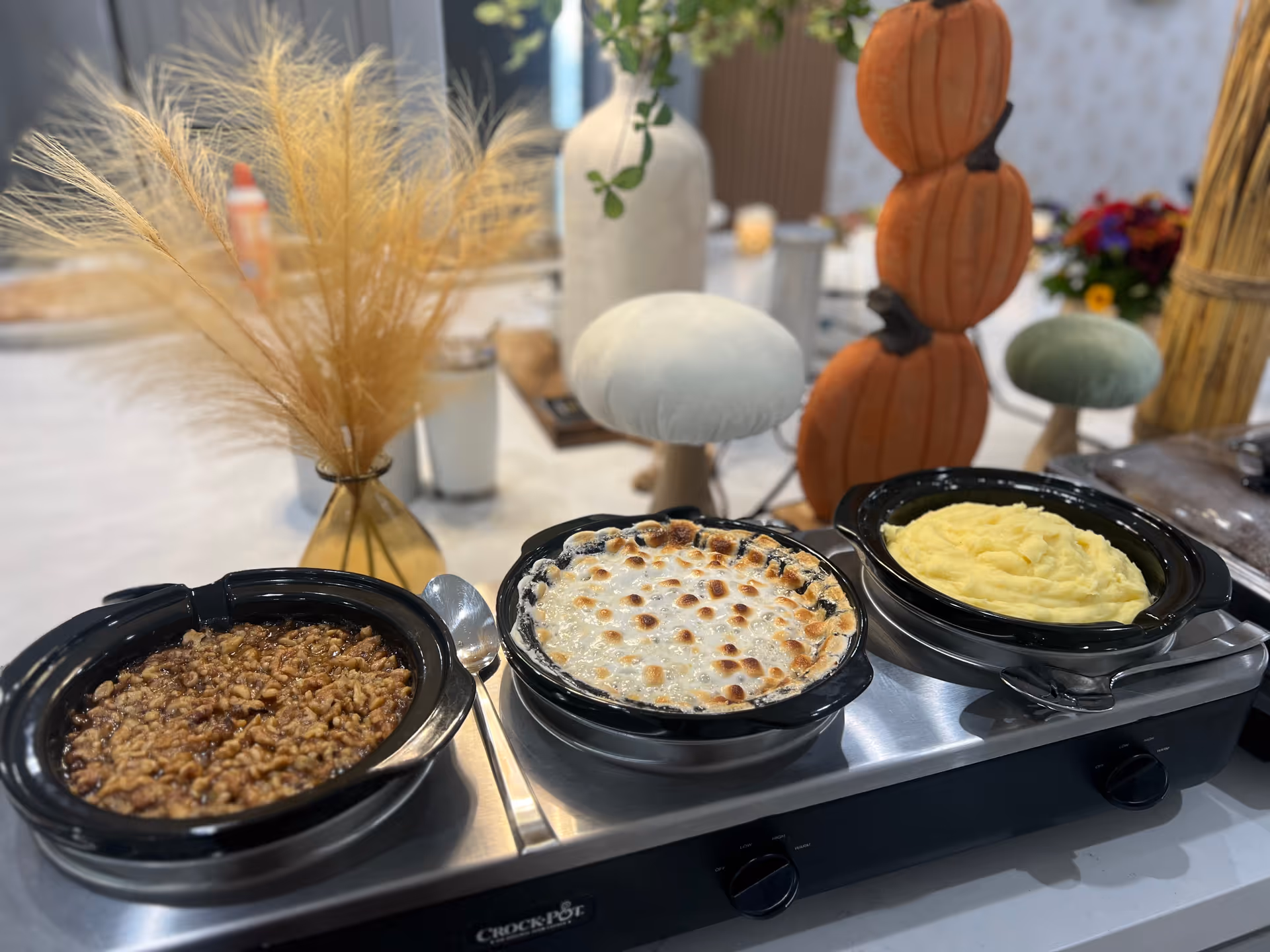 Three heated dishes on a buffet in a decorated dining room.