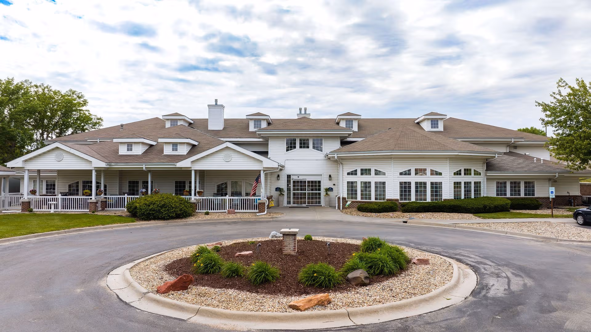 Senior living facility with a circular driveway and white, multi-wing building facade.