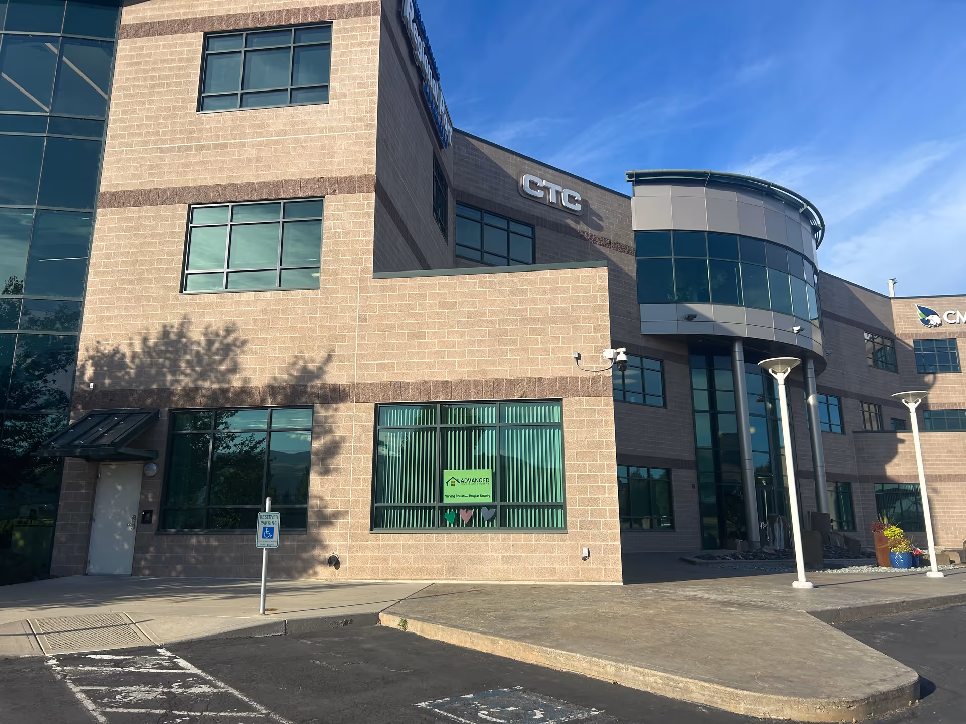 Modern brick exterior building with curved glass entry and clear blue sky.