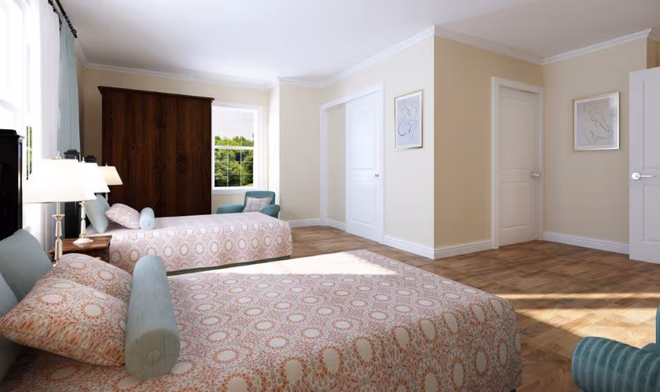 Two twin beds in a light-filled bedroom with beige walls, armoire, and patterned bedding.