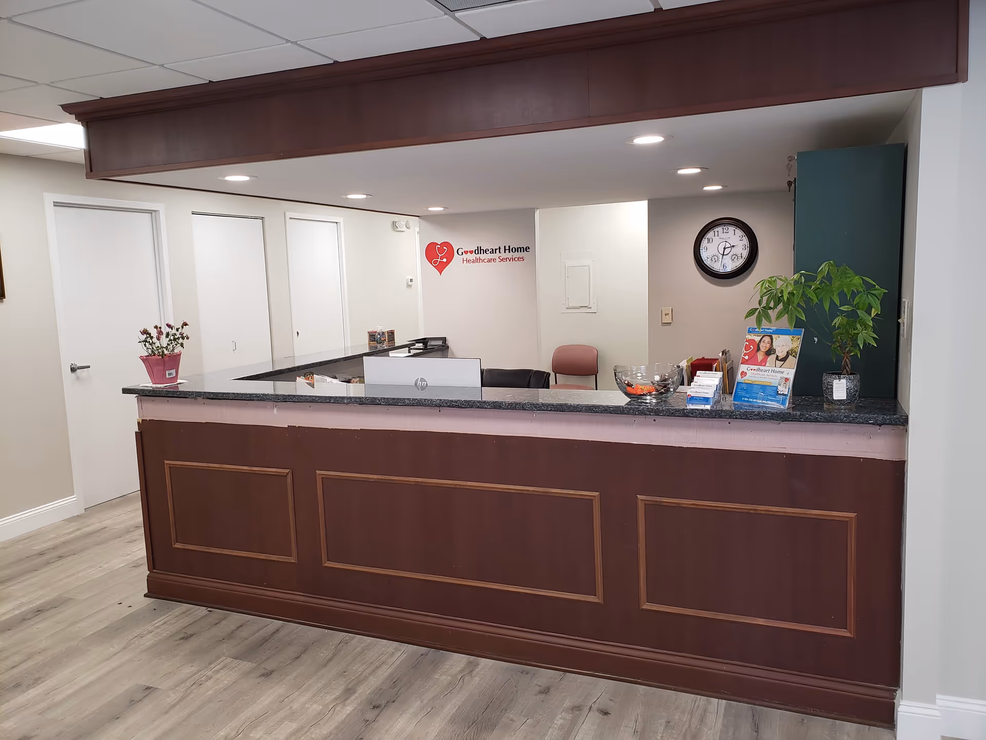 Reception desk in Goodheart Home Healthcare lobby with clock, plant, and brochures