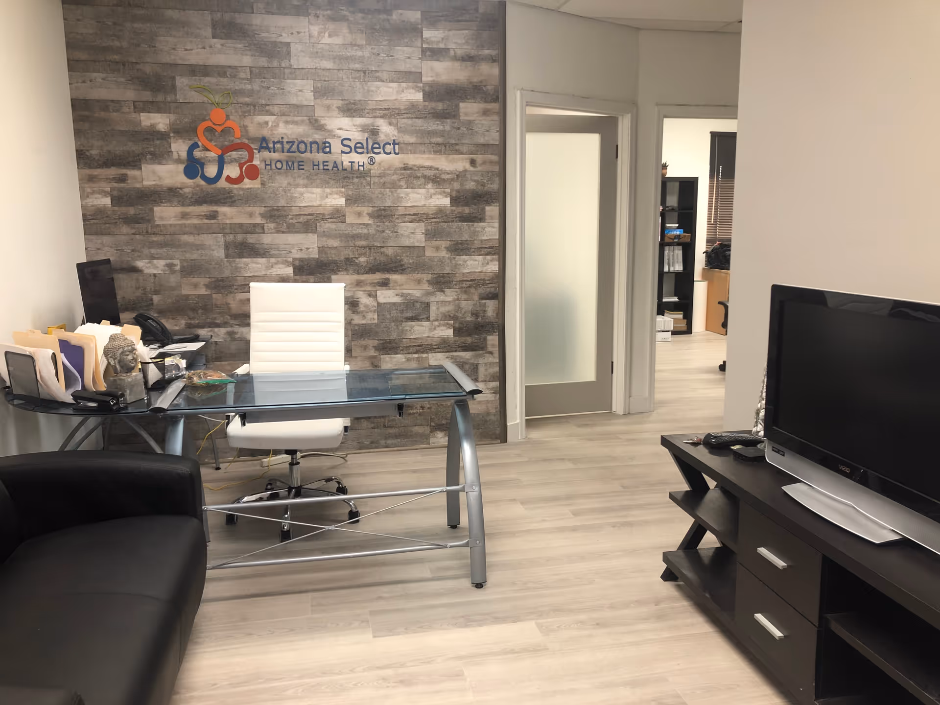 Reception area with glass desk, white chair, and Arizona Select logo on a textured wall.