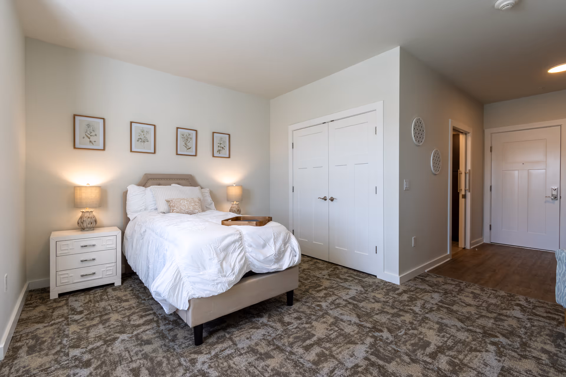 Cozy, neatly made Canopy at Westridge bedroom with white bedding and two lamps.
