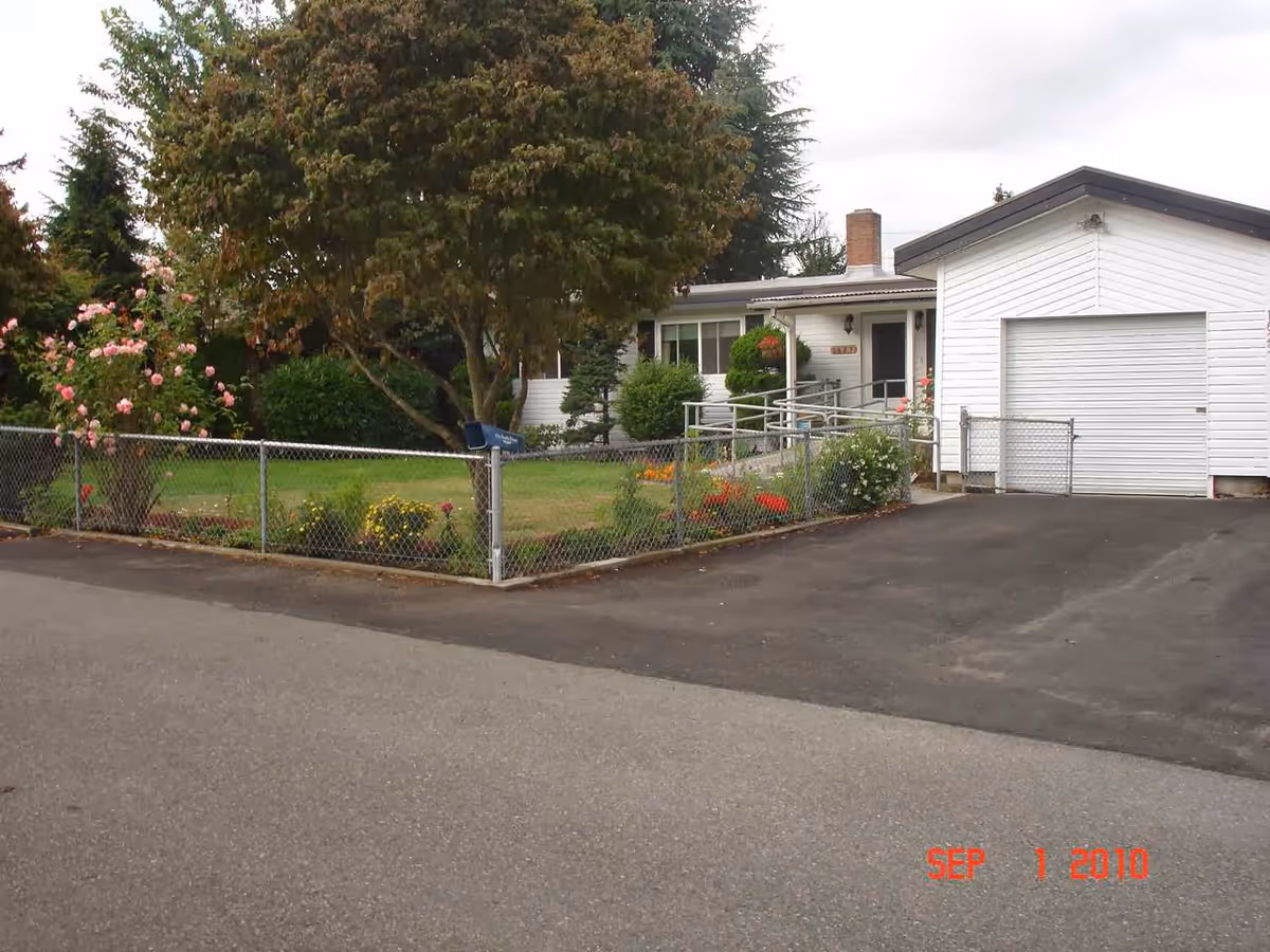 Front exterior view of a white, single-story facility with a fenced lawn and driveway.