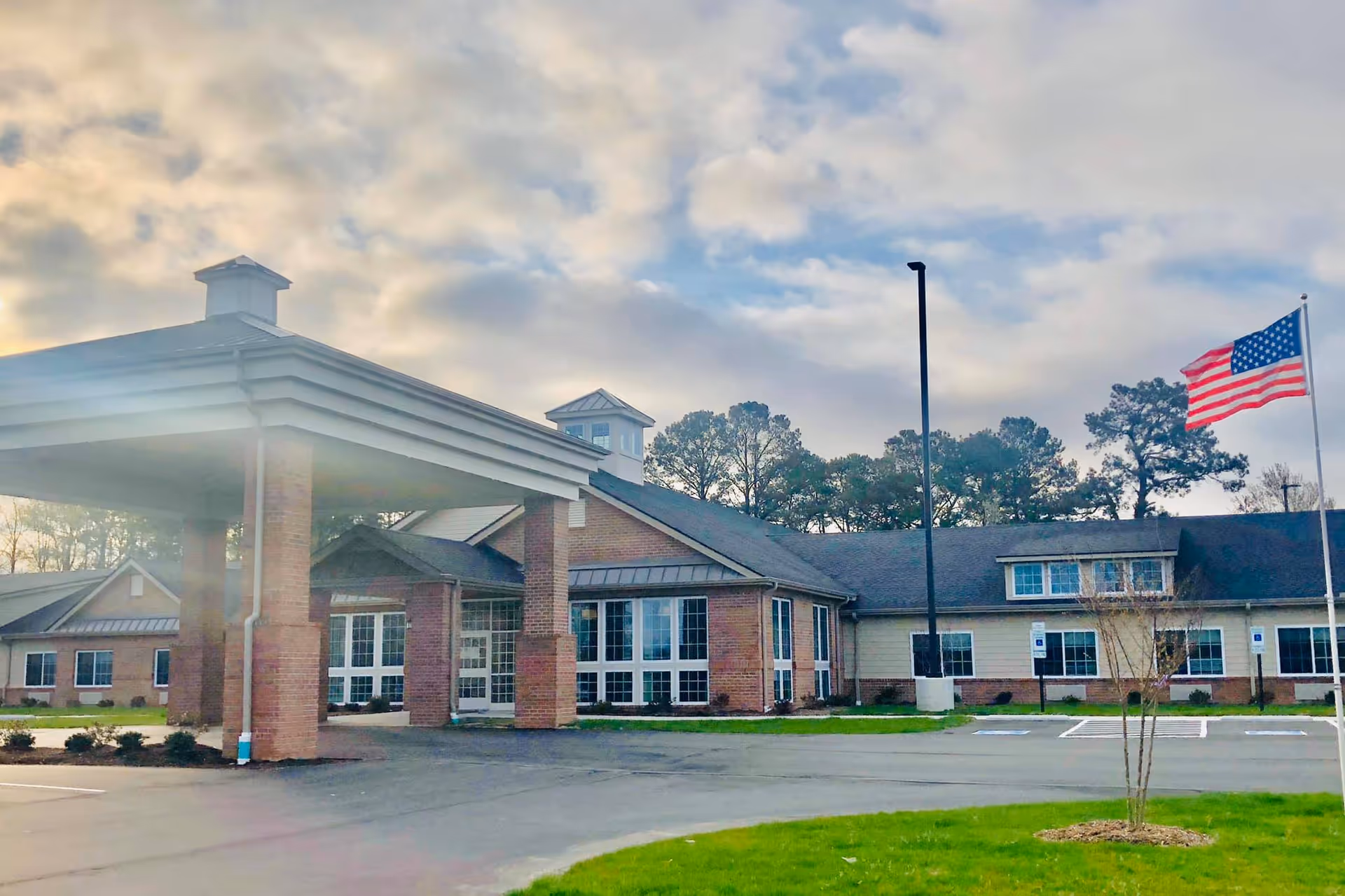 The Landings of Albemarle exterior: brick building with covered entrance, flag, and front parking.